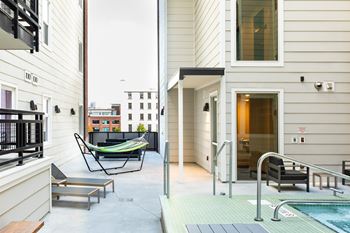 A small balcony with a hammock and a chair.